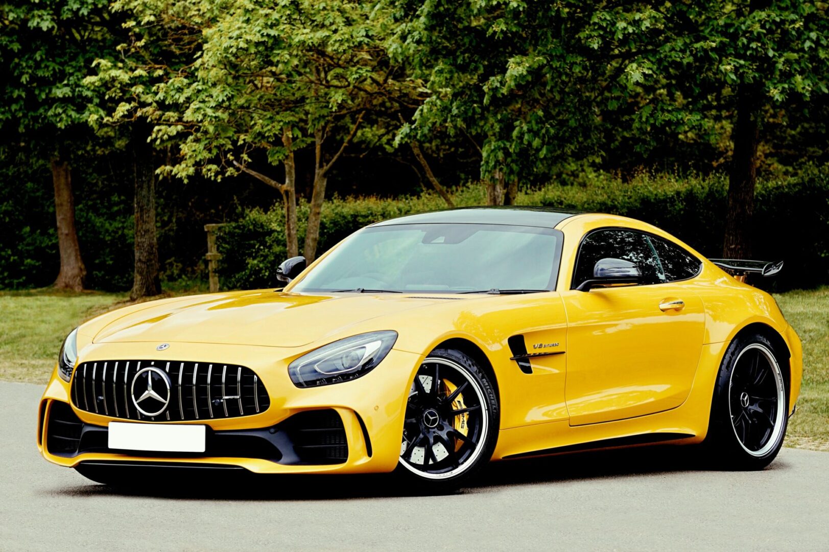 A yellow mercedes benz parked on the side of the road.